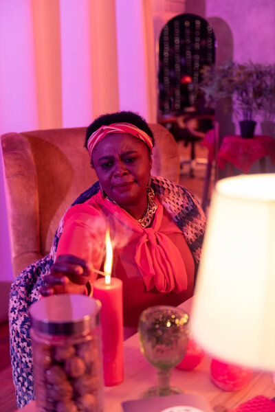 African american plump fortune-teller in ethnic adornments looking concentrated