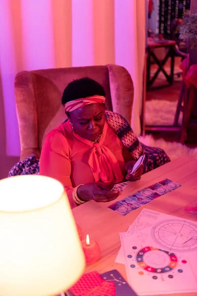 African american plump fortune-teller with huge earrings looking thoughtful — Stock Photo, Image