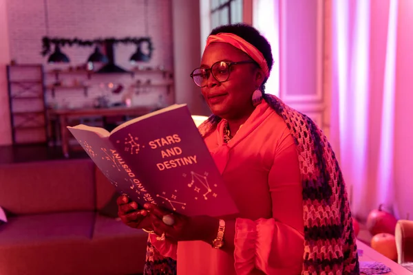 Diseuse de bonne aventure afro-américaine en lunettes lisant un livre sur l'astrologie — Photo