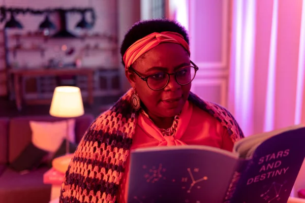 Африканский американец толстый гадалка с большими кольцами держит книгу по астрологии — стоковое фото