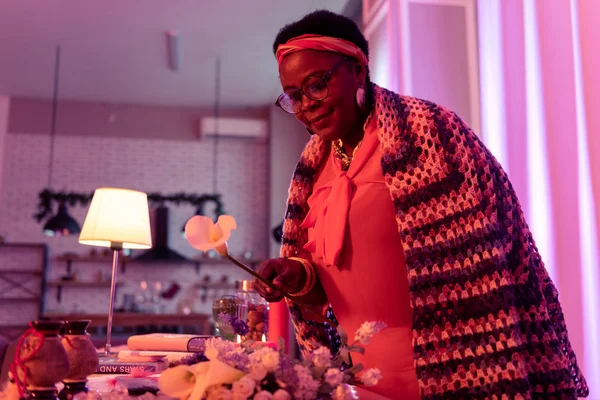 African american plump fortune-teller in eyewear taking a flower — Stock Photo, Image