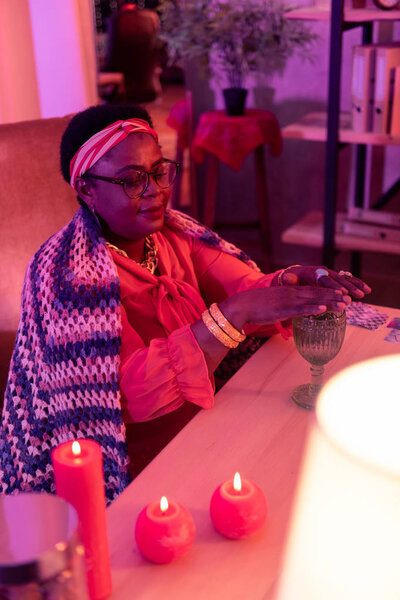 African american plump fortune-teller with a golden watch looking contented