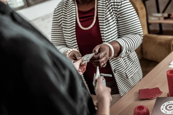 Mujer afroamericana regordeta en una chaqueta a rayas tomando dinero de un cliente — Foto de Stock