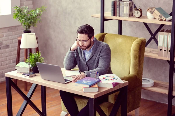 Joven serio sentado frente a la laptop — Foto de Stock