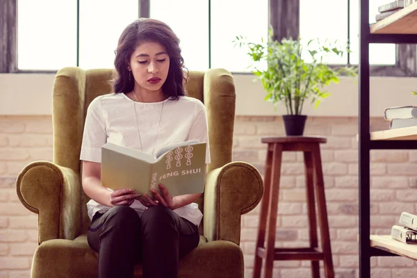 Buena mujer inteligente leyendo un libro sobre feng shui — Foto de Stock