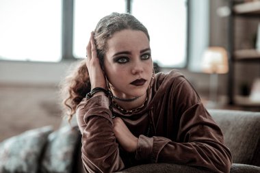 Aksesuarlar giyen ve koyu makyaj sahip mavi gözlü genç