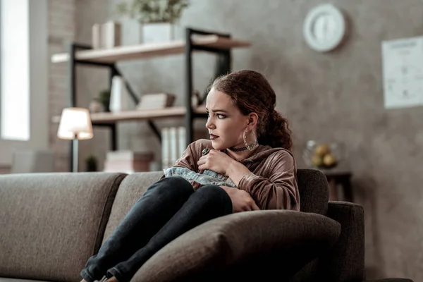 Дівчина-підліток почувається самотньою і нещасною, сидячи на дивані вдома — стокове фото
