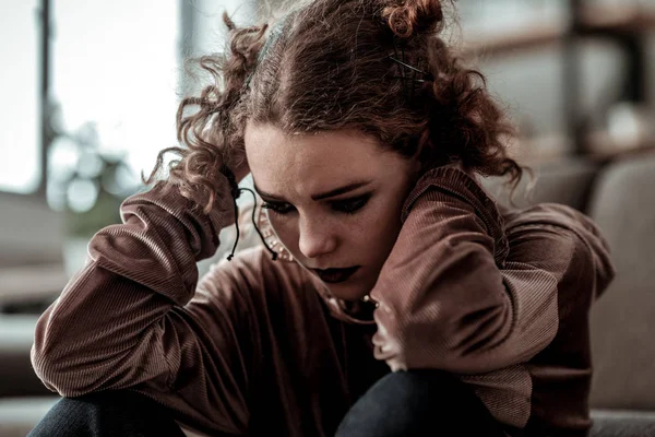 Curly teenage girl with dark makeup feeling bad after divorce of parents