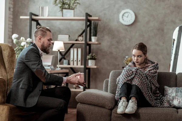 Bearded psychologist talking to stressed young teenage girl