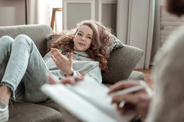 Curly teenage girl feeling positive while talking to counselor — Stock Photo, Image