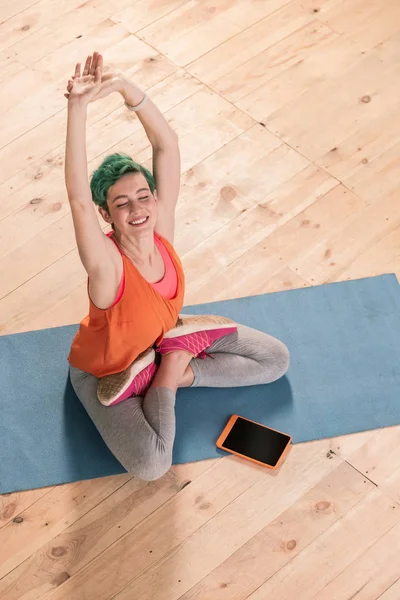 Businesswoman stretching her body sitting on sport mat