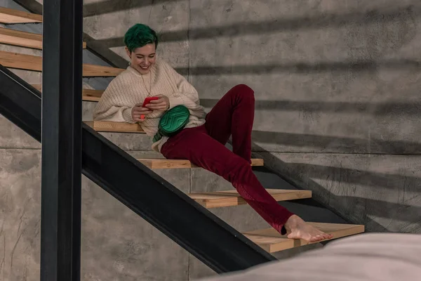 Stylish woman sitting on stairs in her spacious apartment