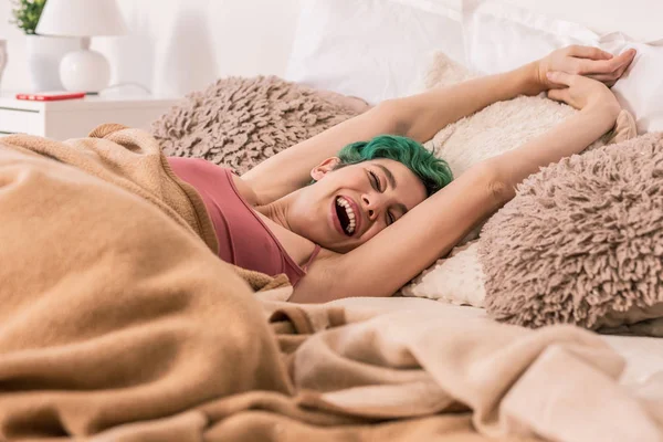 Позитивна усміхнена жінка розтягується вранці лежить в ліжку — стокове фото