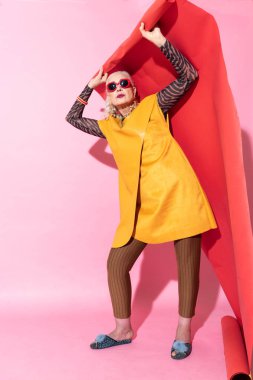 Olgun kadın ayakta pembe arka plan üzerinde memnun