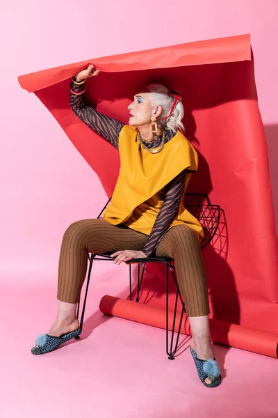 Attraktive weibliche Person sitzt über rotem Hintergrund — Stockfoto
