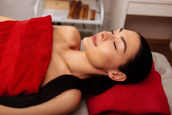Friedliche dunkelhaarige attraktive Frau liegt auf Massagebett — Stockfoto