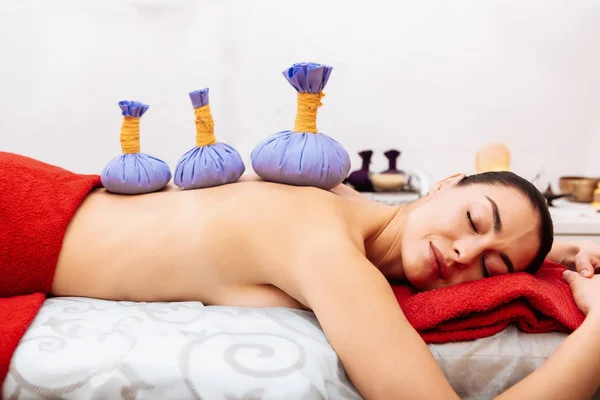 Pleasant dark-haired woman with flawless skin resting on massage bed — Stock Photo, Image