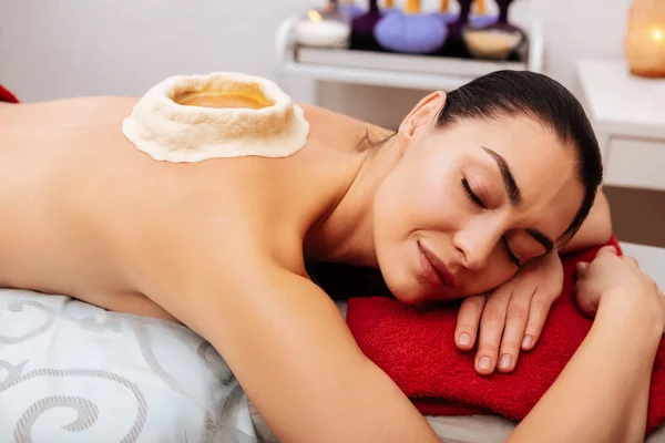 Mujer tranquila de cabello oscuro tumbada pacíficamente en la cama de masaje — Foto de Stock