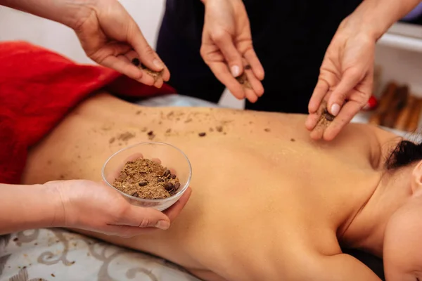 Masters in salon putting scrub made with coffee beans on back — Stock Photo, Image