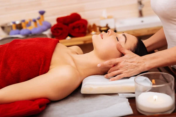 Lugna sömnig kvinna täckt med röd handduk på massagebänk — Stockfoto