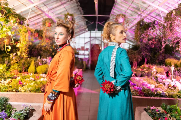 Leuke serieuze vrouwen permanent met rode bloemen — Stockfoto