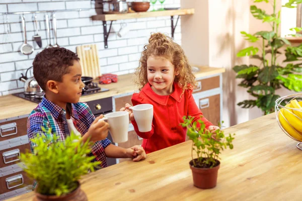 Fröhliche Kinder sitzen zusammen am Tisch — Stockfoto