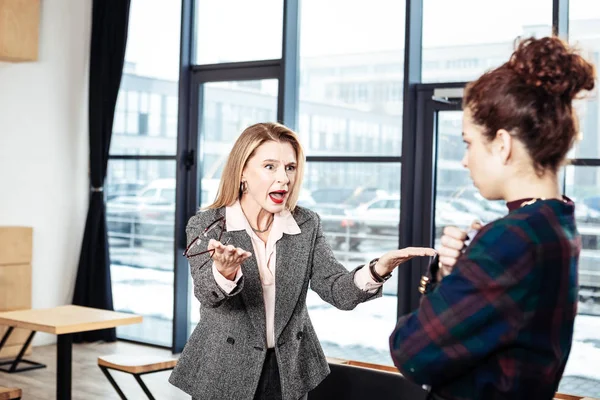 Эмоциональная деловая женщина кричит на свою новую ленивую секретаршу — стоковое фото