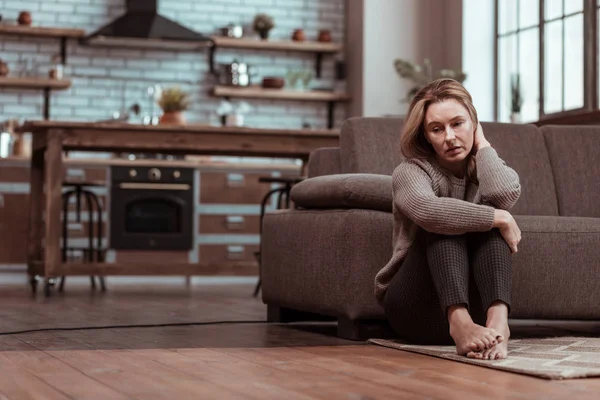 Depressieve vrouw zittend op de vloer terwijl gevoel benadrukt — Stockfoto