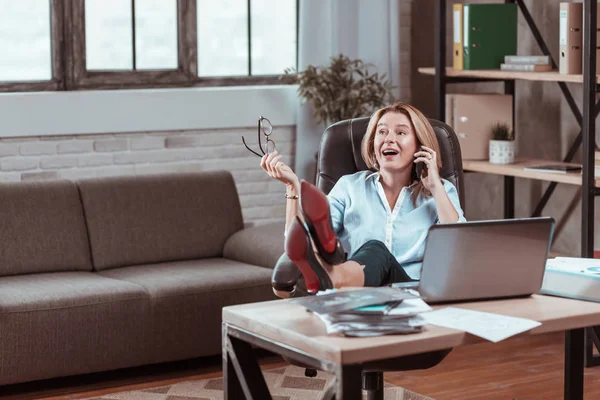 Mulher de salto alto colocando pernas na mesa falando no telefone — Fotografia de Stock