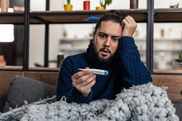 Netter fröhlicher kranker Mann überprüft sein Thermometer — Stockfoto