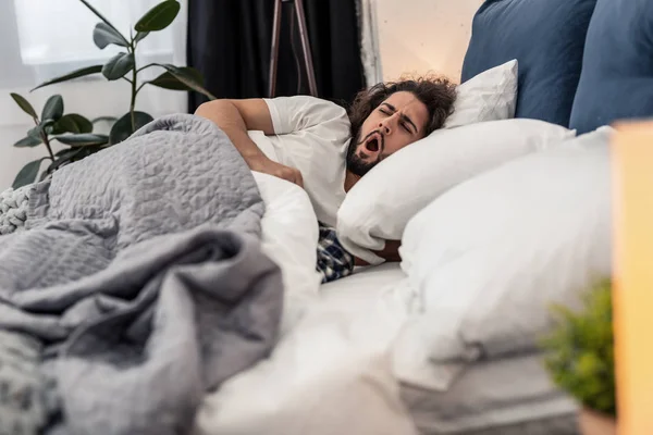 Joven soñoliento bostezando en la cama — Foto de Stock