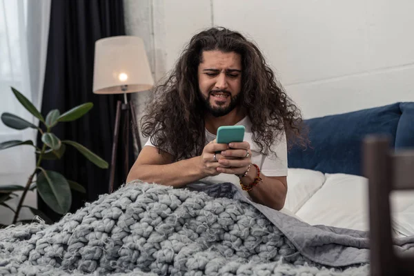 Triste hombre estresado mirando la pantalla de su teléfono inteligente — Foto de Stock