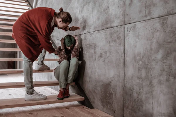 Hombre golpeando a su novia sentada en las escaleras y escondiendo su cara — Foto de Stock
