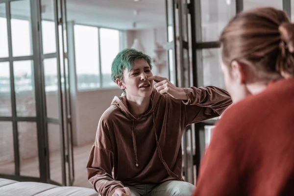 Green-haired wife showing broken nose to man always beating her