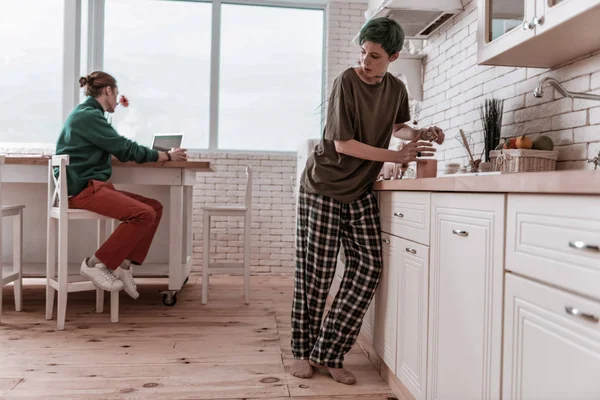 Girlfriend wearing pajamas hiding from man and drinking alcohol