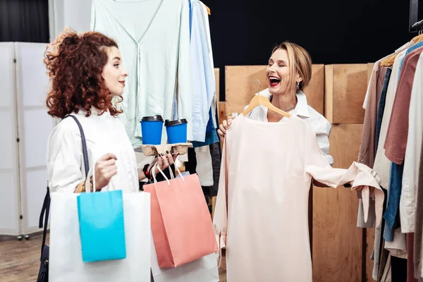 Mother laughing while choosing new dress with daughter — Stock Photo, Image