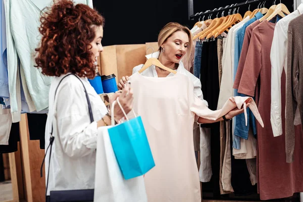 Holding askı dükkanda uzun bej elbise ile anne — Stok fotoğraf