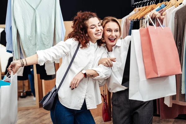 Madre e hija sonriendo saliendo de la tienda con bolsas de ropa — Foto de Stock