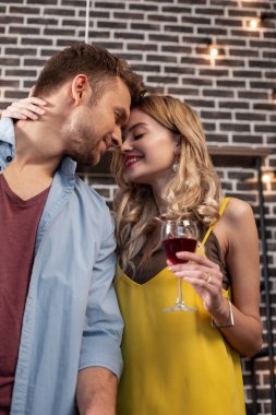 Kıvırcık kadın şarap içme yakışıklı erkek arkadaşıyla sarılma