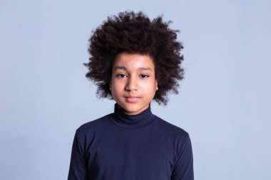 Monochromic arka plan üzerinde poz vahşi saç modeli ile sakin Afro-Amerikan çocuk
