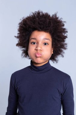 African American dark-haired kid inflating cheeks while wearing blue turtleneck clipart