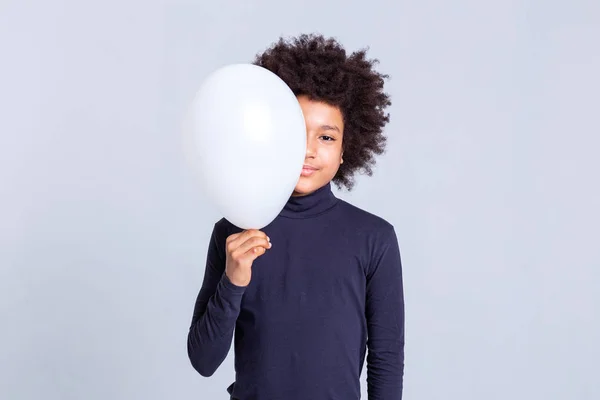 Docela mladík s afro účesem zavírání polovinu jeho tvář s balónem — Stock fotografie