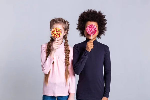 Flaco niños inusuales llevando grandes caramelos de colores en palo —  Fotos de Stock