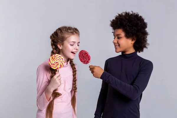 Sonriente chico negro afroamericano proponiendo su caramelo rojo —  Fotos de Stock