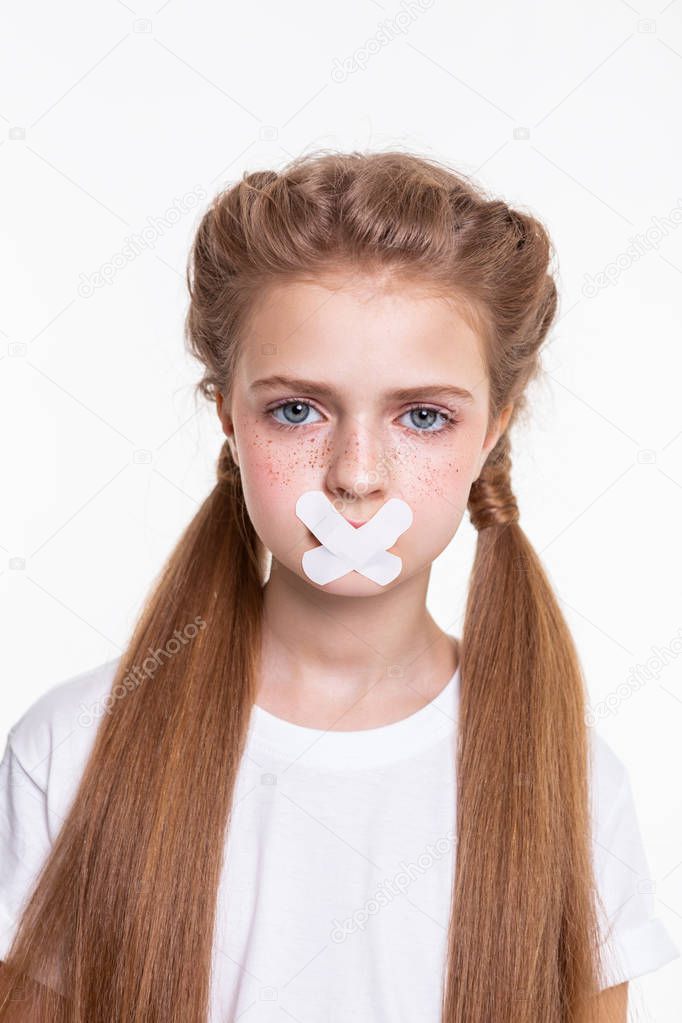 Appealing long-haired little girl in white t-shirt being sad