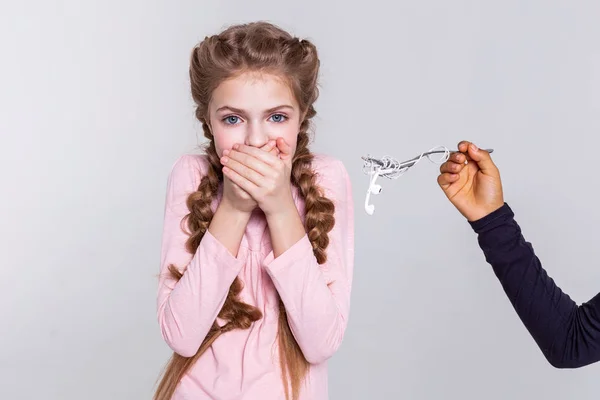 Afraid long-haired girl closing her mouth with both hands — Stock Photo, Image