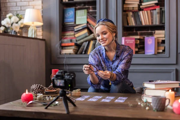 Mujer joven positiva sosteniendo una cadena de cuentas — Foto de Stock