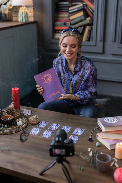 Belle femme positive montrant un livre sur l'ésotérisme — Photo