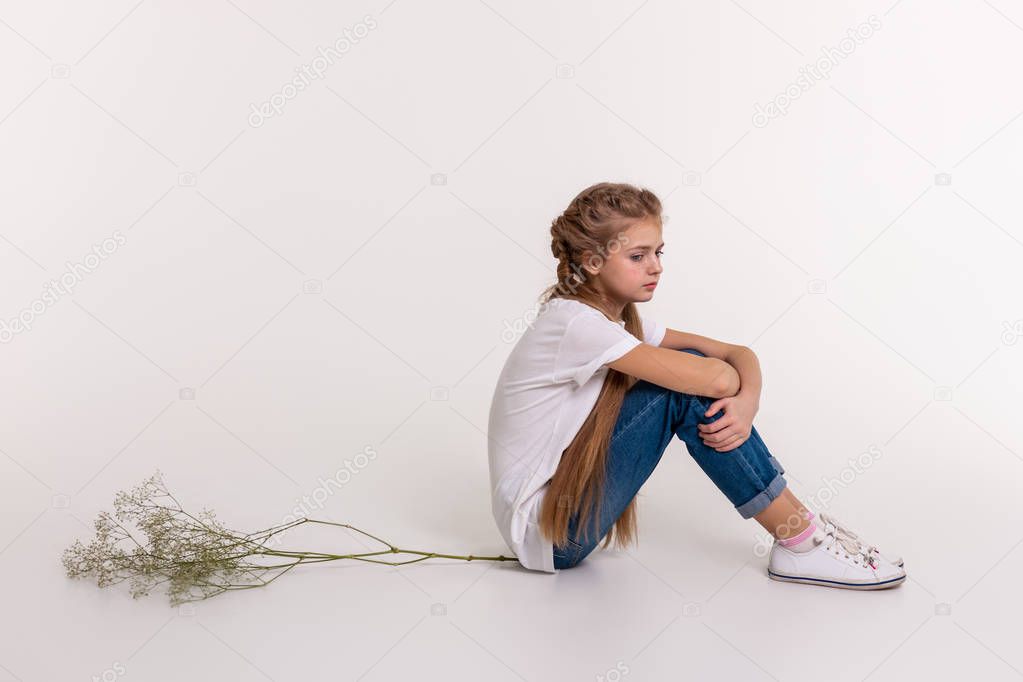 Upset young girl with extremely long hair sitting in closed posture