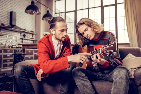 Los participantes de la banda de música se sienten ocupados mientras tocan su nueva guitarra — Foto de Stock